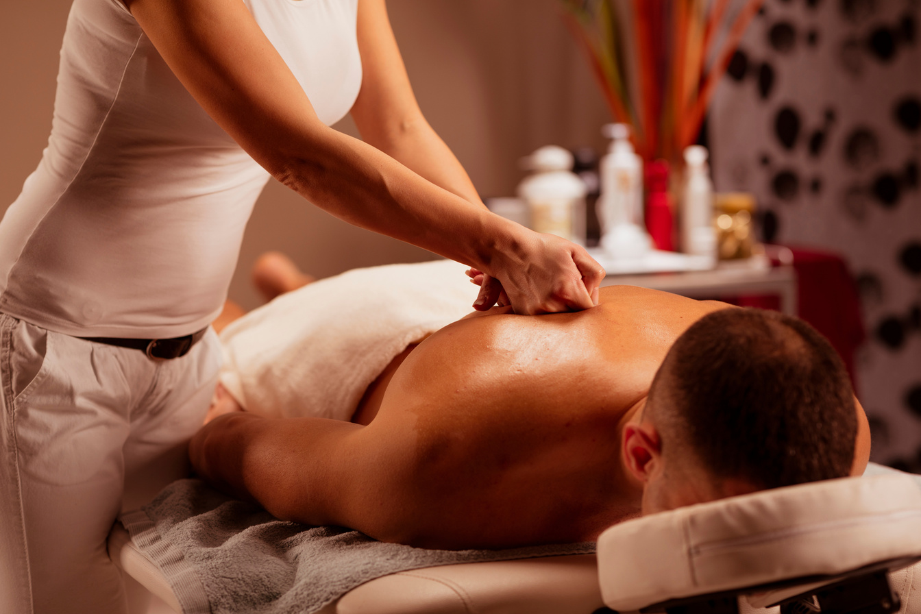 Massage Therapist woman doing healing massage. Man enjoying in relaxing massaging at health spa treatment.